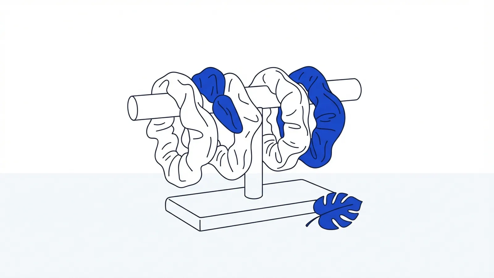 Several plain fabric hair ties draped over a stand with a tropical leaf.